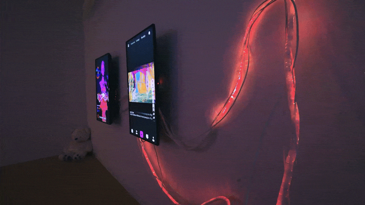 Looping shot of the two screens with the LED strip beside them cycling through the colours of the emotional data stream.